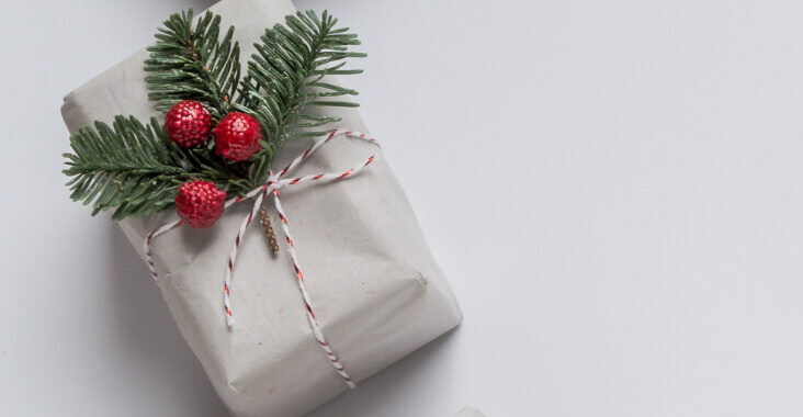 A Christmas gift wrapped in paper, string and foliage