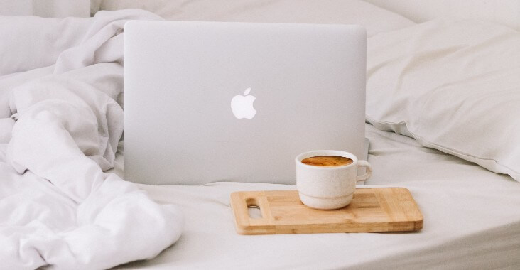 Laptop on bed with coffee
