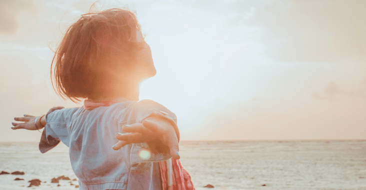 Lady with her arms wide open facing the sun